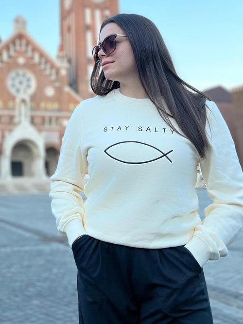 Cream Stay Salty ichthys embroidered crewneck, Christian and Catholic apparel, worn by a woman on Dóm Square below the Votive Church in Szeged, Hungary